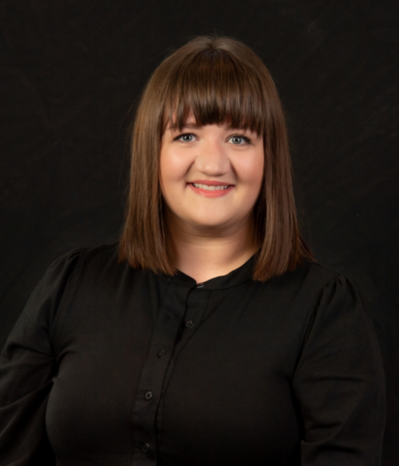"Woman posing for a headshot photo with a black background"