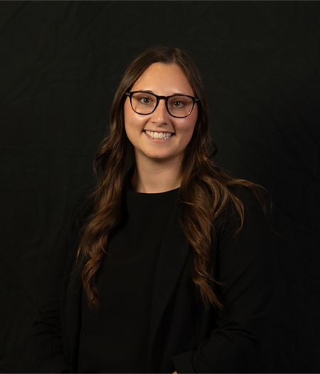 "Woman posing for a headshot photo with a black background"
